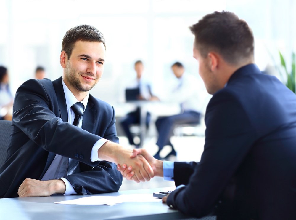 Zwei Geschäftskollegen schütteln die Hände bei einer Besprechung.